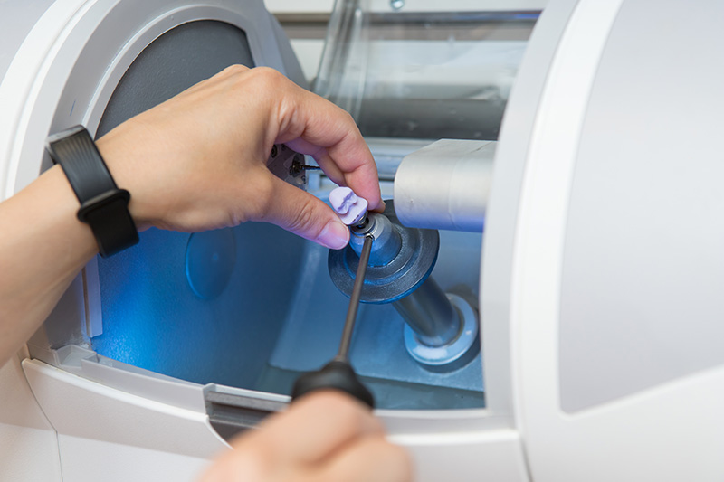 woman sets a workpiece in a dental milling machine for the manuf