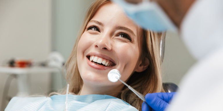 Image of pretty woman sitting in dental chair while professional