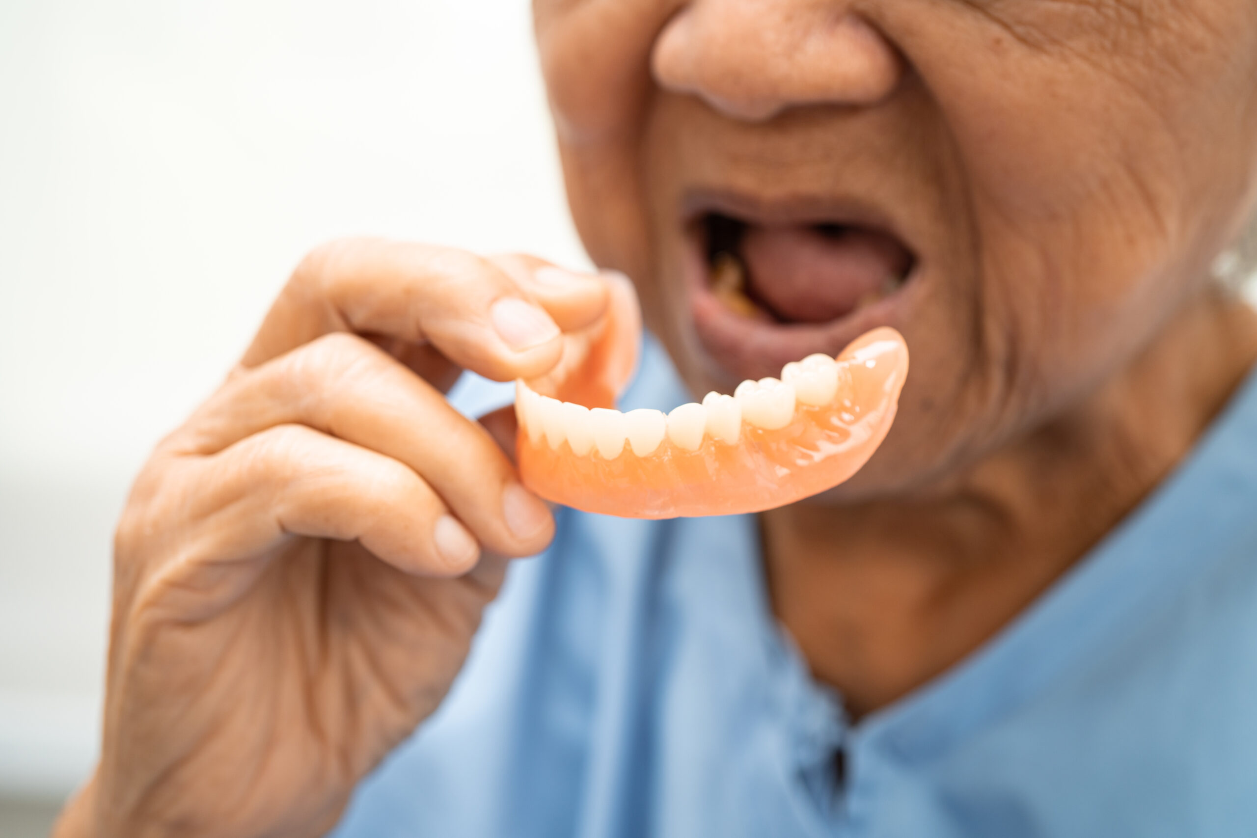 Asian elderly woman patient holding to use denture, healthy stro