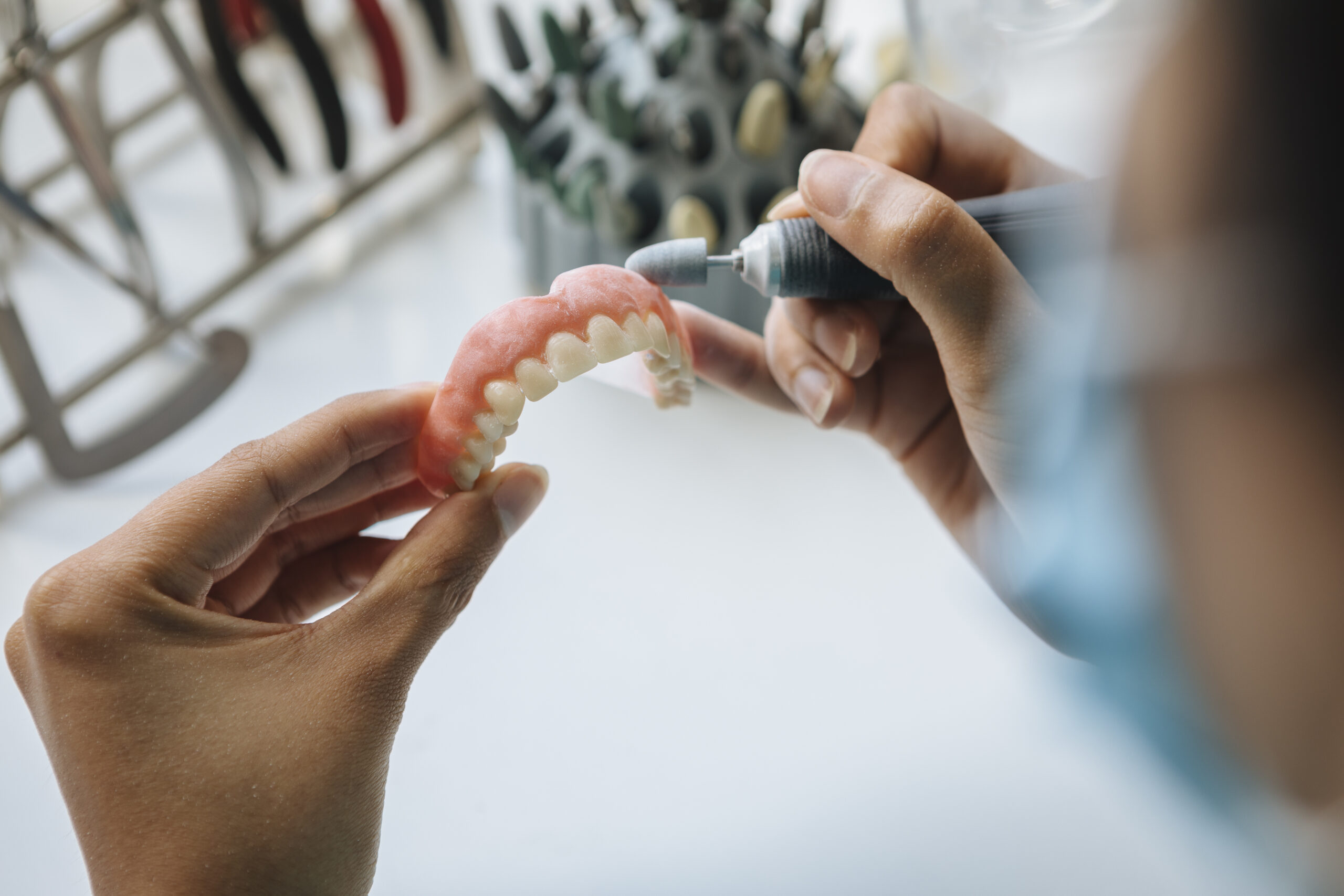 Closeup shot of hands working on a denture with a tool